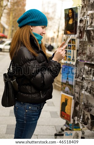 Beautiful tourist in Paris choosing a souvenir postcard