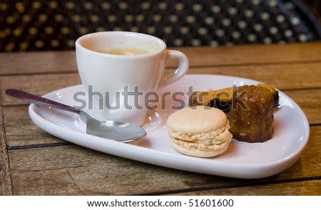Gourmand coffee in a Parisian cafe. Served with traditional French sweets - macaroon cookie, eclair pastry and canele