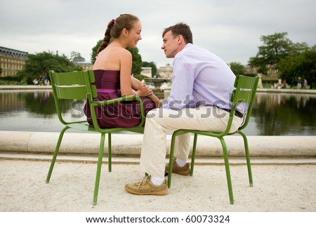 Romantic couple in Paris, sitting on green chairs in Tuileries garden