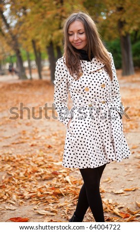 Beautiful young woman in polka dot trench at fall