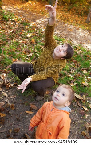 Mother and son in autumn forest, looking at plane in the sky