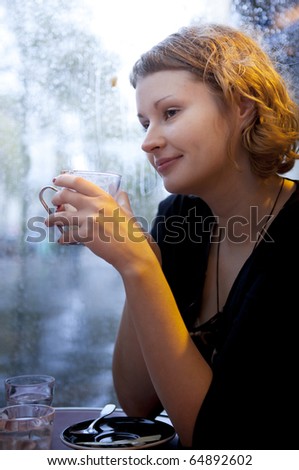 Beautiful girl drinking cappuccino in a Parisian cafe at rain