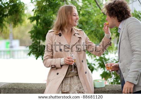 Young beautiful couple in Paris, eating macaroons and drinking champagne