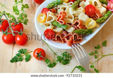 Romantic dinner. Delicious heart-shaped pasta with tomatoes, asparagus and fresh herbs