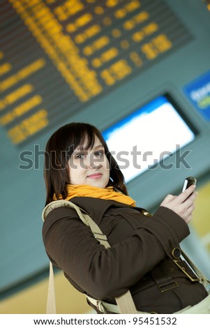 Beautiful young girl sending sms in airport