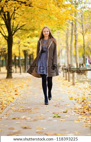 Happy beautiful girl walking in park on a fall day