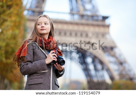 Beautiful girl holding photo camera near the Eiffel tower in Paris