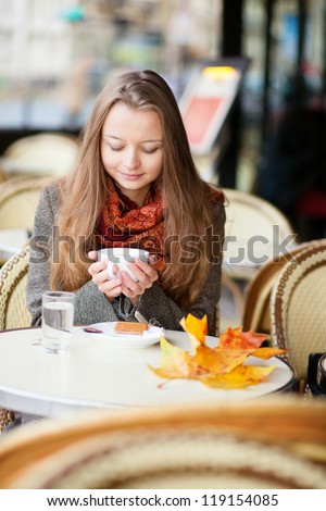 Girl in a cafe with autumn leaves on the table