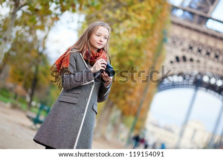 Beautiful girl with photo camera near the Eiffel tower in Paris
