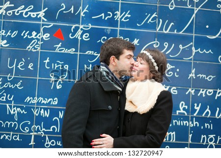 Romantic couple kissing across the I Love You wall in Paris