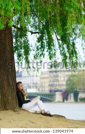 Girl reading under a tree in Paris