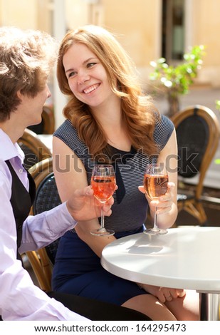 Beautiful couple having a date in a cafe and drinking rose wine