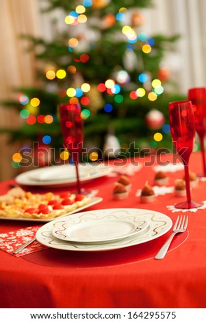 Decorated christmas dining table with champagne glasses and christmas tree in background