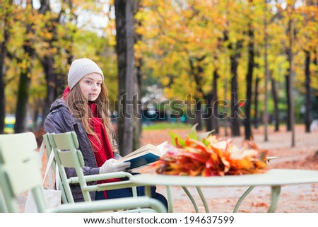 Girl reading a book in an outdoor cafe in Paris