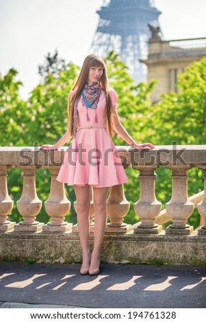 Beautiful girl in pink dress near the Eiffel tower in Paris