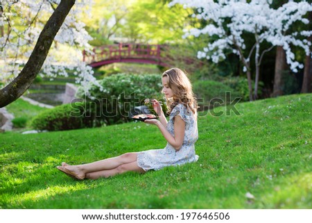 Young European woman eating sushi in Japanese style park