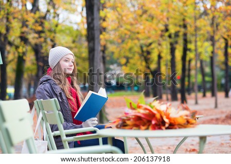 Girl reading a book in an outdoor cafe in Paris