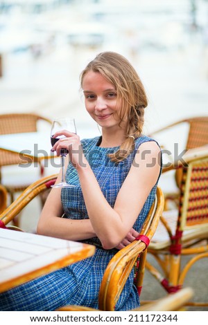 Young French woman drinking red wine in an outdoor cafe of Cannes