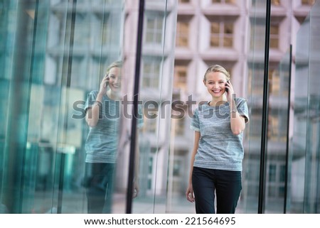 Young beautiful business woman in modern glass interior speaking on the phone