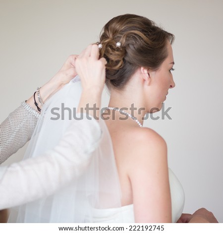 Mother or bridesmaid helping young beautiful bride to get dressed for the wedding