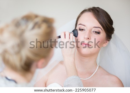 Stylist making up young beautiful bride before wedding