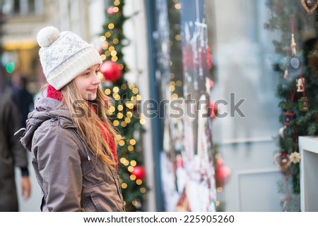 Young girl looking at Parisian shop-windows decorated for Christmas