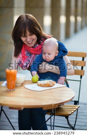 Beautiful young mother with her baby boy having fun together in cafe