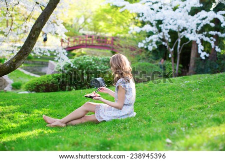 Beautiful young girl eating sushi in cherry blossom garden on a spring day