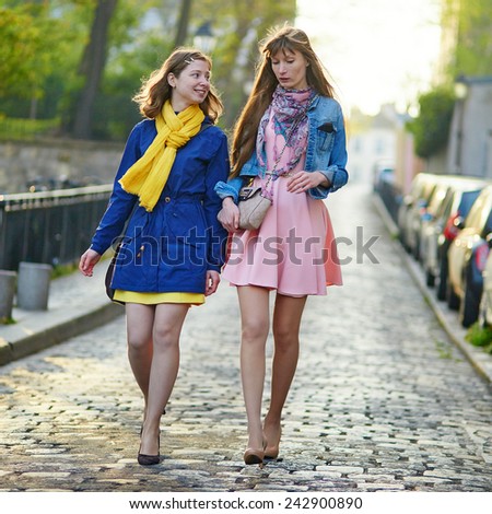 Two cheerful girls walking in Paris together and chatting