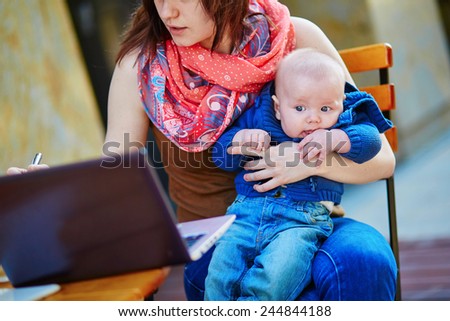 Young working mother with her little son in a cafe