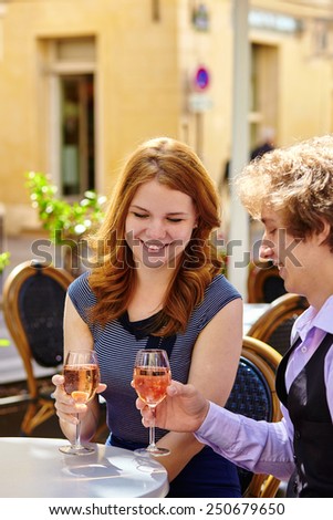 Beautiful couple having a date in a Parisian cafe and drinking rose wine