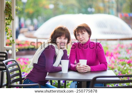 Beautiful middle aged woman with her grown up daughter spending time together and talking in an outdoor cafe