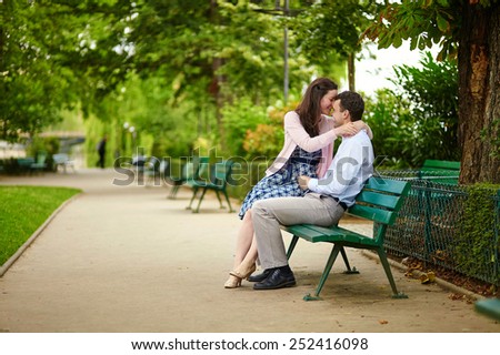 Happy dating couple hugging on a bench in a Parisian park