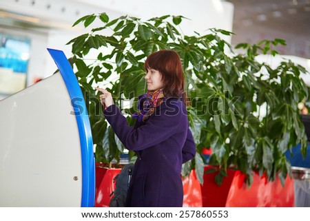 Young female passenger at the airport, doing self check-in