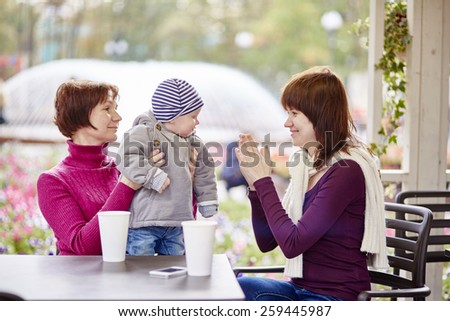 Three generations family - grandmother, mother and little son spending time together in an outdoor cafe