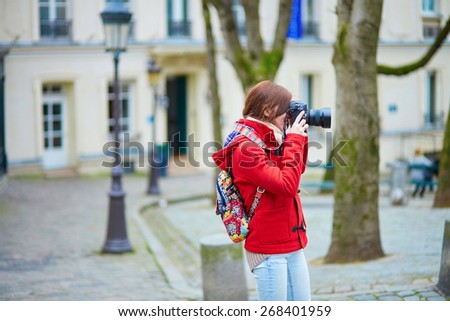 Beautiful young tourist in Paris, taking a photo on the street