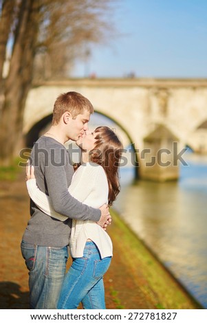 Beautiful romantic couple in Paris kissing near the Seine