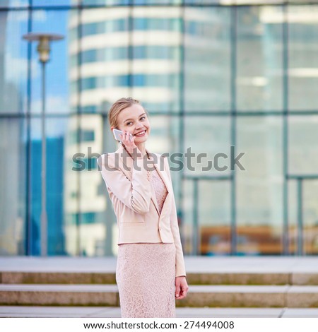 Young confident business woman in modern glass office interior using the mobile phone