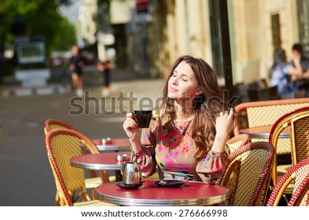Beautiful young woman in Paris, drinking coffee in an outdoor cafe on a nice sunny day