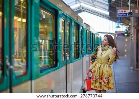 Young beautiful Parisian woman on a subway station, running for her train on the platform