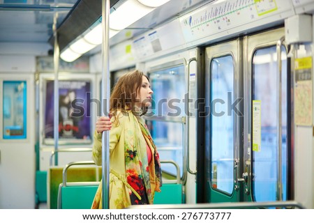 Young beautiful Parisian woman travelling in a subway train, standing near the window