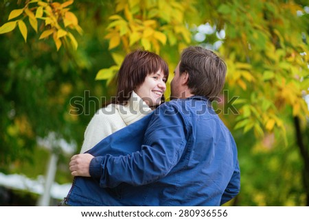 Romantic dating couple in park on a bright fall day, having fun, autumn leaves in the background