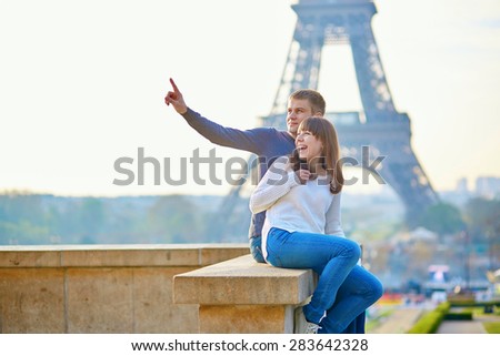 Tourist couple in Paris sitting near the Eiffel tower, man is pointing to something