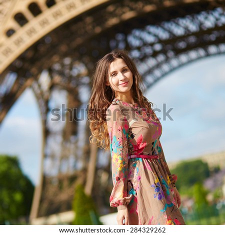 Beautiful young woman walking in Paris under the Eiffel tower on a nice spring or summer day