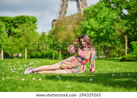 Beautiful young woman in Paris lying on the grass near the Eiffel tower on a nice spring or summer day