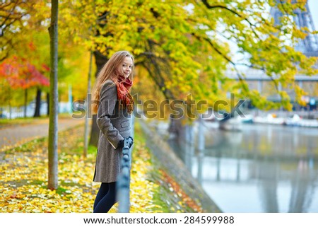 Beautiful young woman in Paris walking on the Isle of the Swans on a beautiful colorful autumn day, Eiffel tower in the background