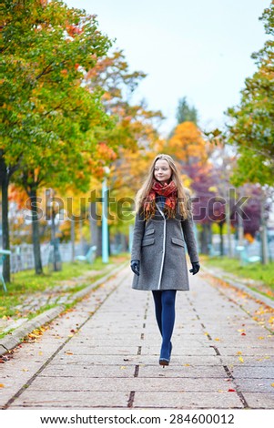 Beautiful young woman in Paris walking on the Isle of the Swans on a beautiful colorful autumn day