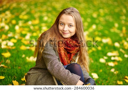 Beautiful young woman in Paris sitting on the ground on a beautiful colorful autumn day