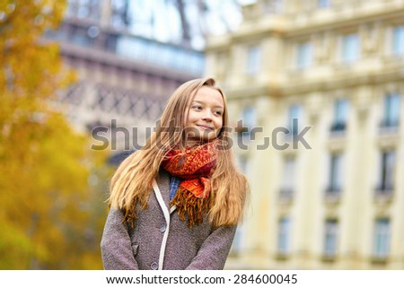 Beautiful young woman in Paris walking near the Eiffel tower on a beautiful colorful autumn day