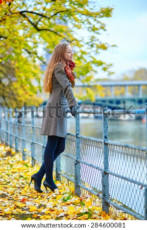 Beautiful young woman in Paris walking on the Isle of the Swans on a beautiful colorful autumn day, Eiffel tower in the background